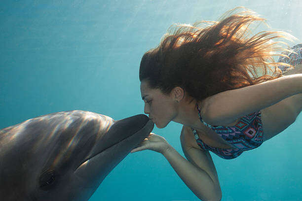 Justin Lewis Umělecká fotografie Young Woman Kisses Dolphin Underwater, Sunbeams, Justin Lewis, (40 x 26.7 cm)