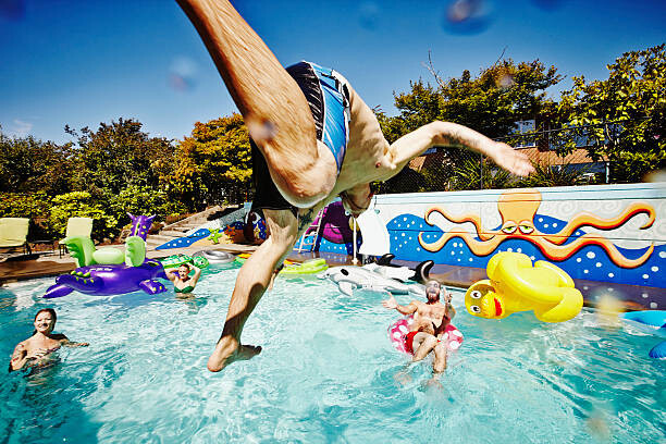 Thomas Barwick Umělecká fotografie Man in mid air jumping into pool during party, Thomas Barwick, (40 x 26.7 cm)