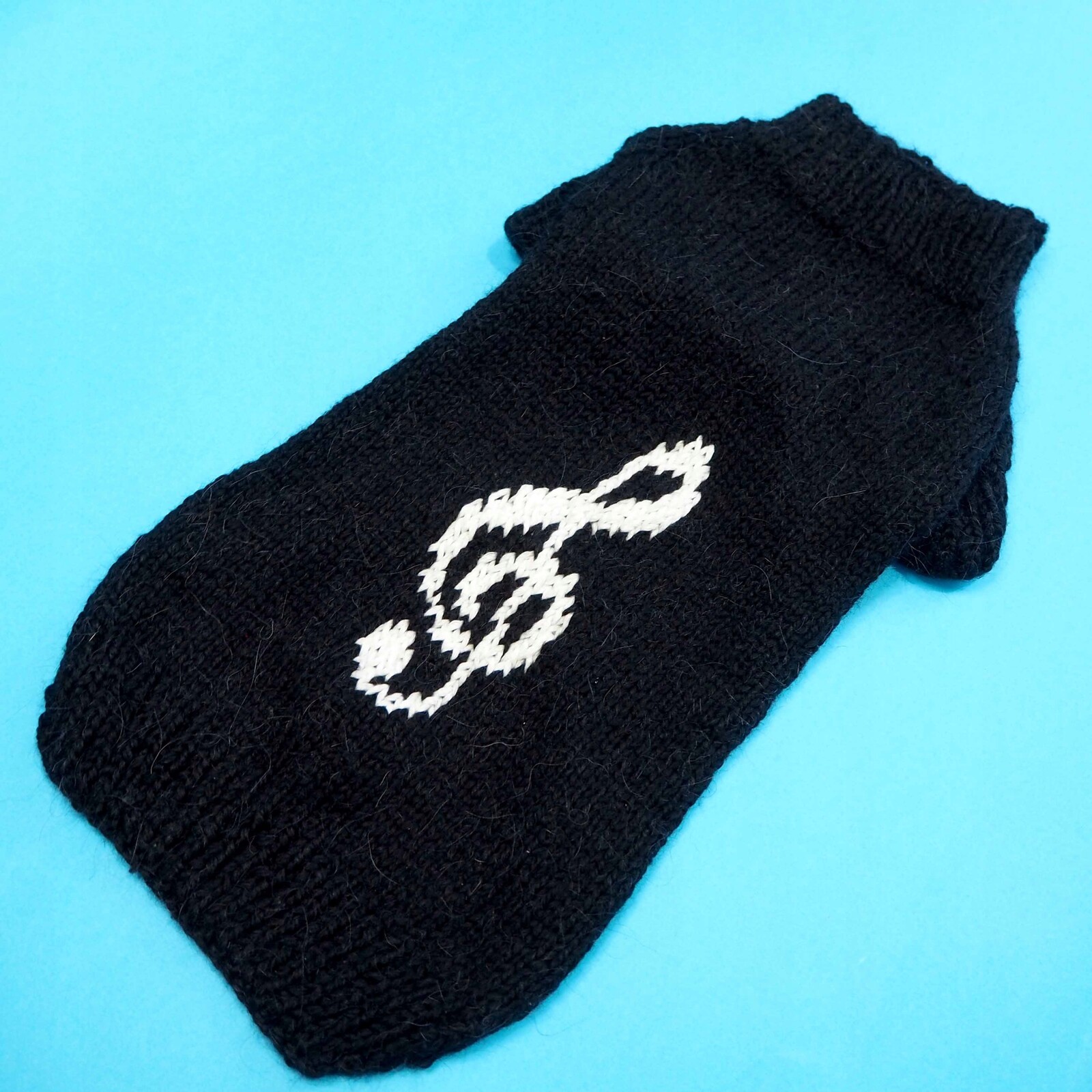 Ručně vyráběný černý svetr pro psa s bílým houslovým klíčem – velikost L