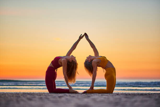 Jose Martinez Plakát, Obraz - Two women doing yoga on the beach at sunrise, Jose Martinez, 40 × 26.7 cm