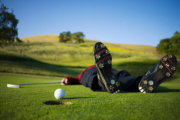 Joe McBride Plakát, Obraz - Golfer lying on green, ball on edge of hole, Joe McBride, 40 × 26.7 cm