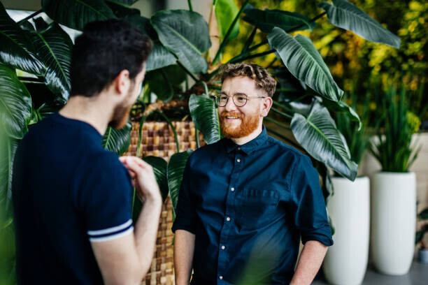 Tom Werner Plakát, Obraz - Two Colleagues Standing Amongst Potted Plants, Tom Werner, 40 × 26.7 cm