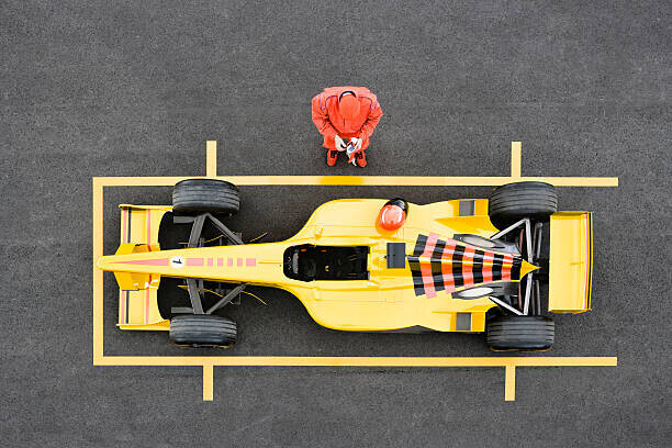 David Madison Plakát, Obraz - Racecar Driver Standing by Racecar Adjusting, David Madison, 40 × 26.7 cm