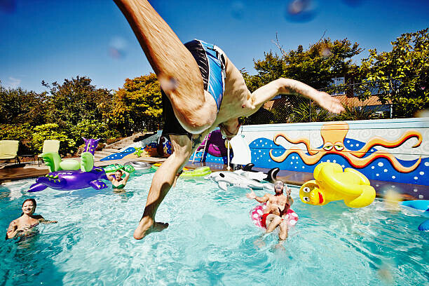 Thomas Barwick Plakát, Obraz - Man in mid air jumping into pool during party, Thomas Barwick, 40 × 26.7 cm