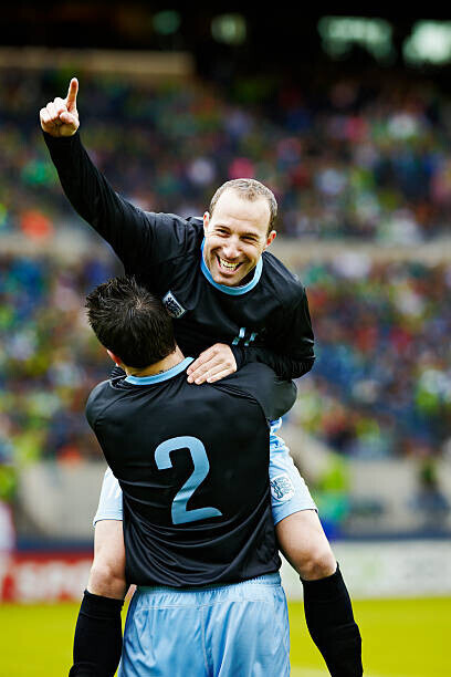 Thomas Barwick Plakát, Obraz - Soccer player jumping into the arms of teammate, Thomas Barwick, 26.7 × 40 cm